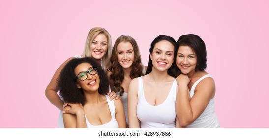amistad, belleza, cuerpo positivo y concepto de personas - grupo de diferentes mujeres felices en ropa interior blanca sobre fondo rosa