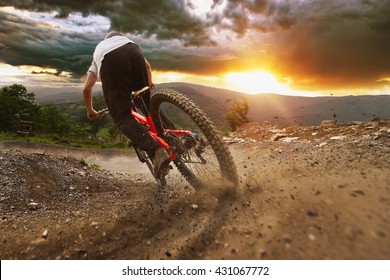Man op mountainbike rijdt op het parcours op een stormachtige zonsondergang.