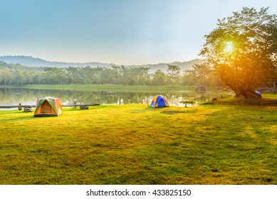 Camping en tent in de buurt van meer in zonsopgang