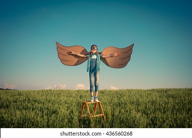 快乐的孩子玩耍。孩子在户外玩得开心。带纸板翅膀的孩子。夏日田野里的孩子。旅行和度假概念。想象力和自由概念