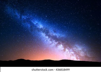 Nachtlandschaft mit bunter Milchstraße und gelbem Licht an den Bergen. Sternenhimmel mit Hügeln im Sommer. Schönes Universum. Raumhintergrund