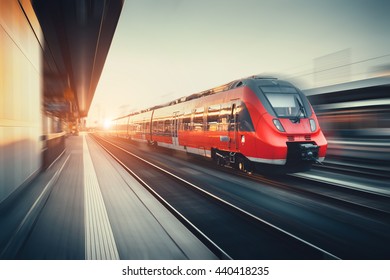 Hermosa estación de tren con moderno tren de cercanías rojo de alta velocidad con efecto de desenfoque de movimiento al atardecer colorido en Nuremberg, Alemania. Ferrocarril con tono vintage