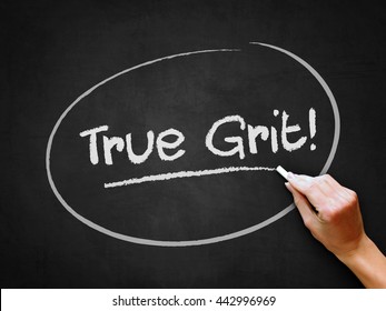 A hand writing 'True Grit!' on chalkboard.