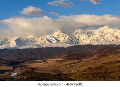 雪と氷河のある美しい山頂、青い空、雲、日の出の日の光に照らされた渓谷の美しい景色