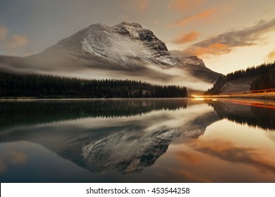 カナダのバンフ国立公園で日没時に反射と霧のある山の湖と信号の道。