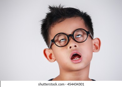 Retrato de un niño asiático con anteojos que muestra un gesto muy perezoso, infeliz, aburrido y cansado