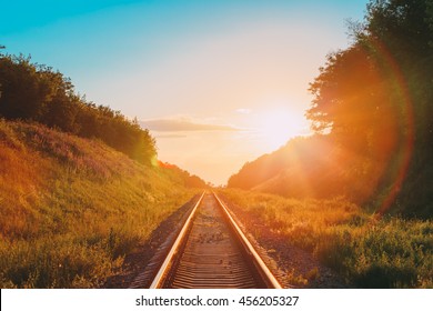 El paisaje escénico con el ferrocarril que va directamente a través de la pradera montañosa de verano hasta el atardecer o el amanecer en la luz del sol. Efecto destello de lente.