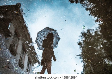 puddle reflection silhouette of girl with umbrella
