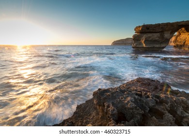 日没時の石灰岩のアーチは、マルタのゴゾ島ドウェルジャにあるアズール ウィンドウとして知られています。この場所は、ゲーム オブ スローンズで、デナーリス ターガリエンがドスラクの武将カール ドロゴと結婚する際の結婚式のシーンとして使用されました。