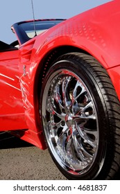 Sportovní červené auto s leštěným chromovaným lemem.