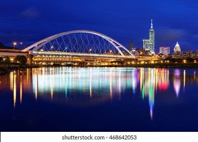 Night scenery of Taipei City with beautiful reflections of skyscrapers & bridges on the water by riverside at dusk ~ Cityscape of Taipei 101 Tower, Keelung River, Xinyi District & downtown in twilight