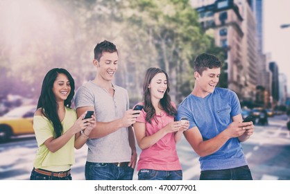 Vier lachende Freunde, die Texte auf ihren Handys gegen die New Yorker Straße senden