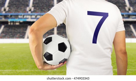 Cropped rearview image of a young player man holding a soccer ball under his arms at the stadium in Madrid
