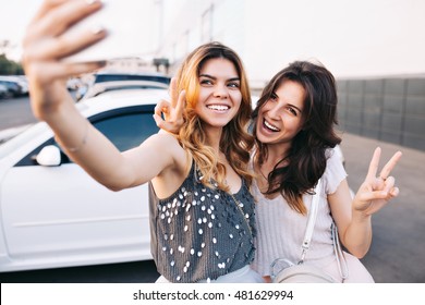 Zwei attraktive modische Mädchen, die Spaß beim Parken haben. Sie machen Selfie-Portrait und sehen glücklich aus