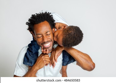 Một cậu bé người Mỹ gốc Phi trên vai cha mình, cúi xuống hôn vào má ông. Cha anh cười với đôi mắt nhắm nghiền.