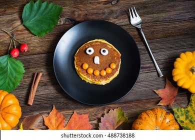 Pumpkin Halloween pancake for kids. Holiday breakfast with smiling face on pancake. Thanksgiving, fall, autumn concept