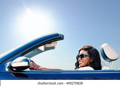 Close up portrait of young african girl taking blue convertible for a test drive.