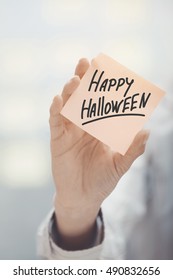 Woman holding sticky note with Happy Halloween text