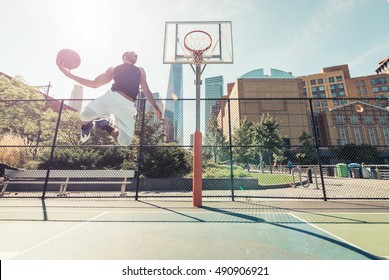コート、ニューヨークの建物の背景に巨大なスラムダンクを実行するストリート バスケット ボール選手