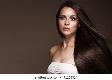 Hermosa chica morena en movimiento con un cabello perfectamente liso y un maquillaje clásico. Cara de belleza Fotografía tomada en el estudio.
