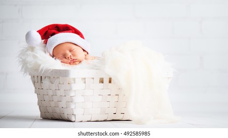 クリスマスサンタ帽をかぶった寝台の生まれたばかりの赤ちゃん