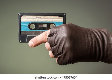 male hand with glove holding an old music tape
