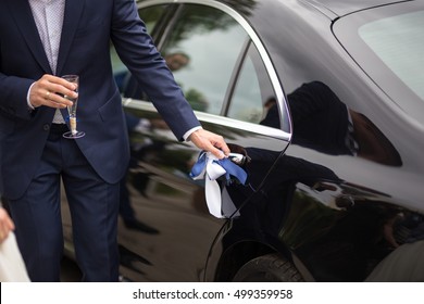 Groom opening the luxury wedding car doors for the bride