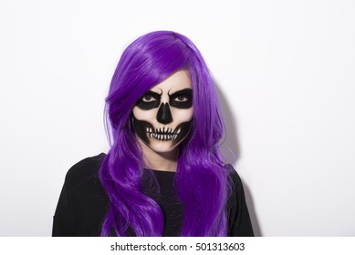 Portrait of woman with terrifying halloween makeup and purple wig over white background