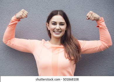jonge sportieve vrouw die pronkt met haar spieren en glimlacht
