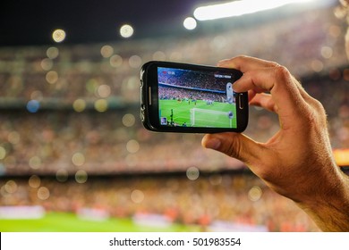 A supporter of F.C. Barcelona football team, recording a goal with his mobile phone camera at the Camp Nou Stadium, Barcelona, Spain.