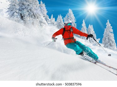 Pemain ski bermain ski menuruni bukit di pegunungan tinggi