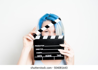 Joven actriz rubia de ojos azules de cerca con badajo de película detrás de la cara
