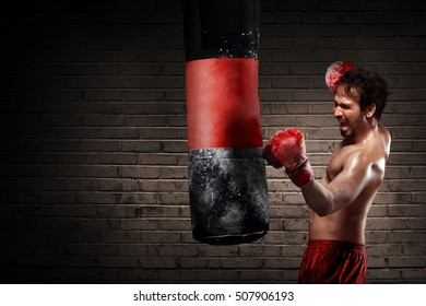 Jonge bokser die traint met het ponsen van de zak over de muurachtergrond
