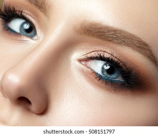美しい金色の色合いと黒のアイライナー メイクで青い女性の目のクローズ アップ表示。クラシックメイク。完璧な眉。スタジオショット