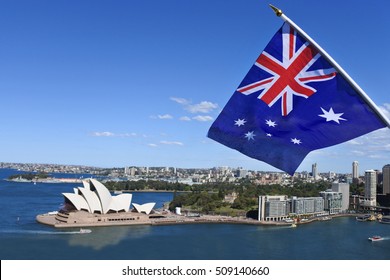 De nationale vlag van Australië wappert boven de haven van Sydney en het operagebouw in Sydney, Australië. Geen mensen. Ruimte kopiëren