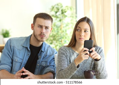 Jaloerse vriend bespioneert zijn vriendin terwijl ze naar haar telefoon kijkt terwijl ze hem van streek kijkt