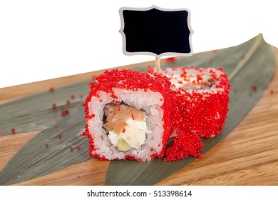 Sushi rolls on wooden Board with leaves of leeks and black sign for logo and name