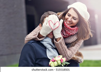 Imagen que muestra a una pareja joven con flores saliendo en la ciudad