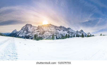 Sinar matahari musim dingin di atas pegunungan bersalju - Panorama bersalju dengan Pegunungan Alpen Austria, hutan konifer hijau, dan lembah yang tertutup salju putih.