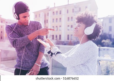 Young multiethnic couple outdoor in the city listening music with head phones - enjoying, music, relaxing concept