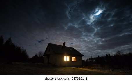 Landschaft mit Haus nachts unter bewölktem Himmel. Gespenstische Landschaft mit Haus in der Nacht.