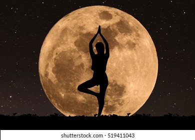 Silueta mujer joven con buena forma practicando yoga bajo la luna llena por la noche con estrellas