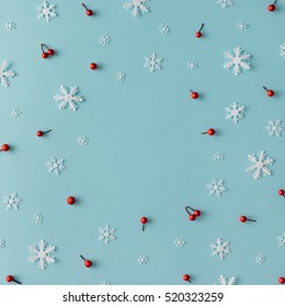 Pola Natal yang terbuat dari kepingan salju dan buah beri merah dengan latar belakang biru. Konsep musim dingin. Berbaring datar.