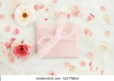 花の装飾が施された手作りのピンクの紙のフェミニンなギフト、繊細で美しいバラの花と花びら、パステル トーン。リボン弓。