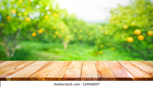 Meja kayu dengan taman oranye kabur di pagi hari. Untuk tampilan produk montase atau desain tata letak visual utama