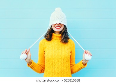 Mode glückliche junge Frau in Strickmütze und Pullover, die Spaß über buntem blauem Hintergrund haben