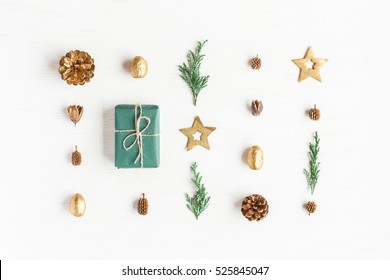 Composición navideña. Regalo, decoraciones doradas de Navidad, ramas de ciprés, conos de pino sobre fondo blanco. Vista plana, vista superior