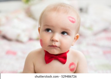 Image of adorable child with red kisses on the skin, happy boy, sitting in the Studio on the bed, angel, romantic holiday, Valentine's Day.