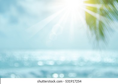Desenfoque de hoja de palma verde hermosa naturaleza en playa tropical con fondo abstracto de onda de luz de sol bokeh. Copie el espacio de las vacaciones de verano y el concepto de viajes de negocios. Estilo de color de filtro de tono vintage.