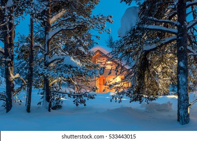 暗い寒い冬の森に暖かい光のある木造住宅 – 冬のおとぎ話の風景
